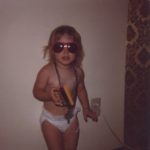 Jessica holds her big sister's Owl calculator, wearing tons of bead necklaces and big sunglasses in this classic diaper-clad photo. (8/1979)